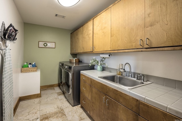 laundry area featuring baseboards, separate washer and dryer, a sink, cabinet space, and marble finish floor
