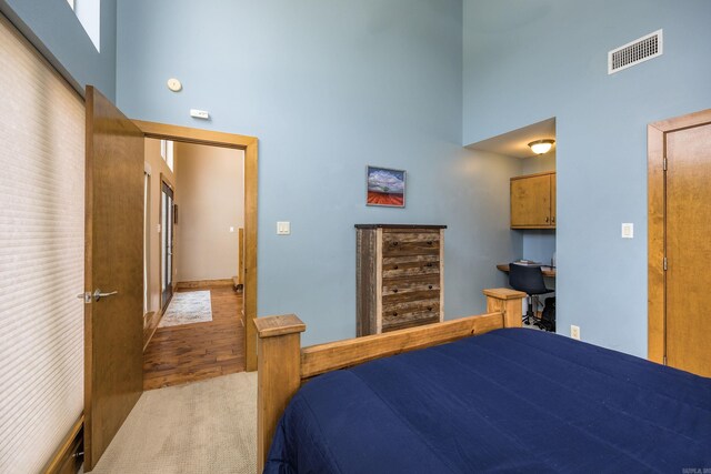 bedroom featuring visible vents, wood finished floors, and a towering ceiling