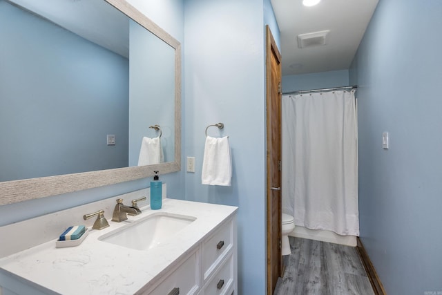 full bath with vanity, baseboards, toilet, visible vents, and wood finished floors