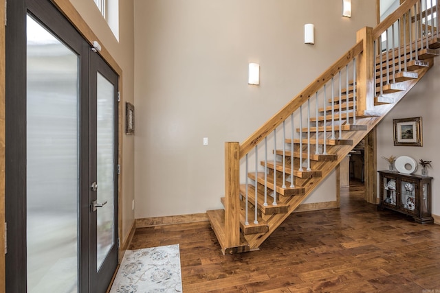 foyer entrance featuring a high ceiling, wood finished floors, baseboards, and stairway