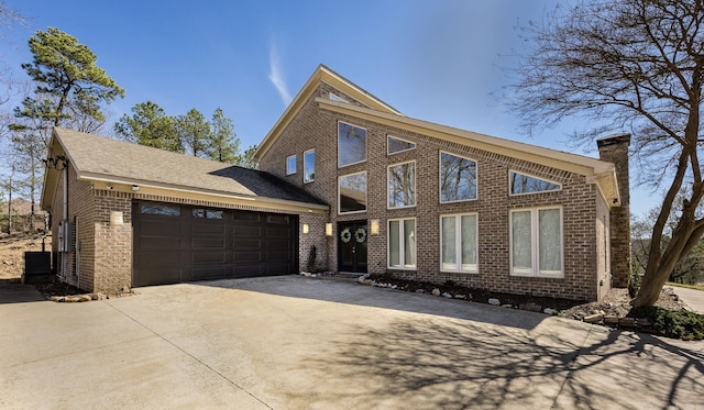 view of front of property with an attached garage, a chimney, concrete driveway, and brick siding