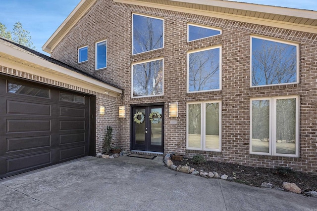 view of front of home with brick siding, driveway, french doors, and an attached garage