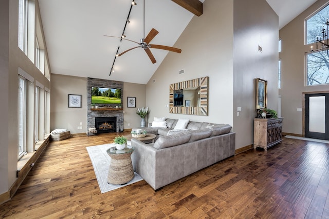 living area with baseboards, a fireplace, hardwood / wood-style floors, ceiling fan, and high vaulted ceiling