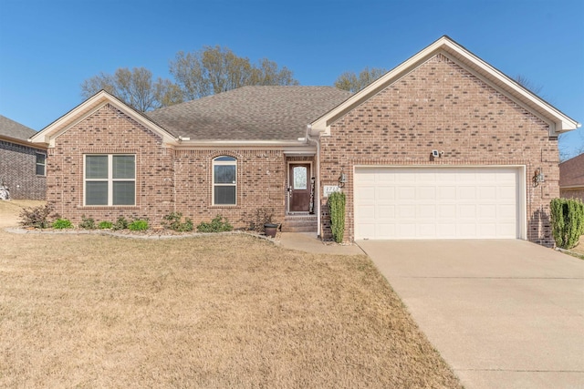 ranch-style home featuring an attached garage, concrete driveway, brick siding, a front lawn, and roof with shingles