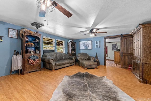 344 Rockwood Ln, Clinton, AR 72031 - living room featuring a textured ceiling, a barn door, light wood finished floors, and ceiling fan