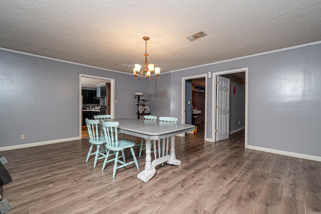 dining room with baseboards, visible vents, wood finished floors, and an inviting chandelier