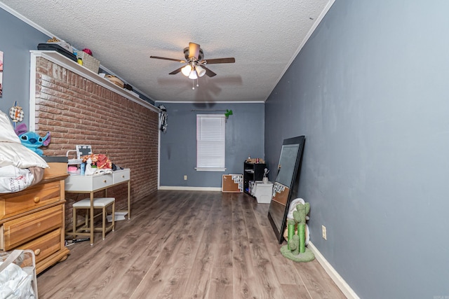 bedroom featuring baseboards, a textured ceiling, wood finished floors, and crown molding