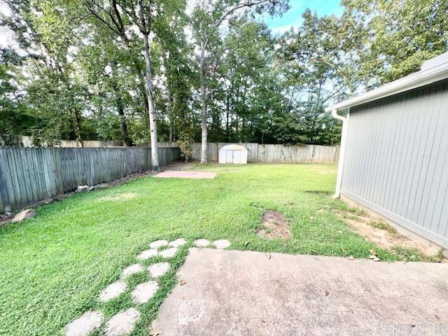 view of yard with an outdoor structure, a fenced backyard, and a storage shed