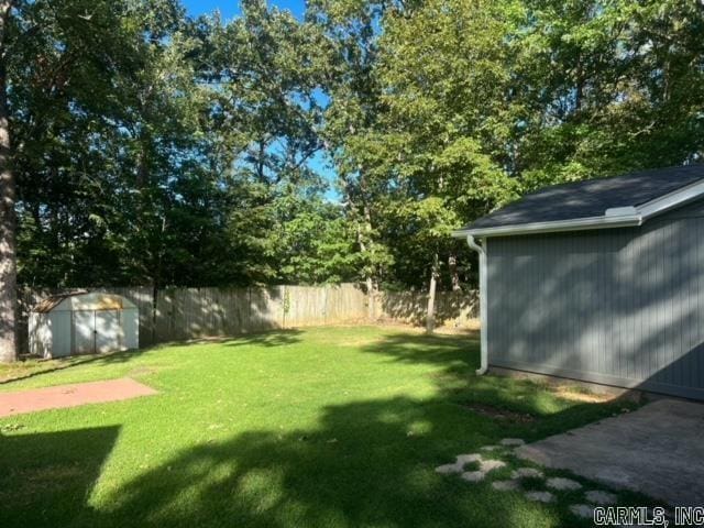 view of yard featuring an outdoor structure, a shed, and fence