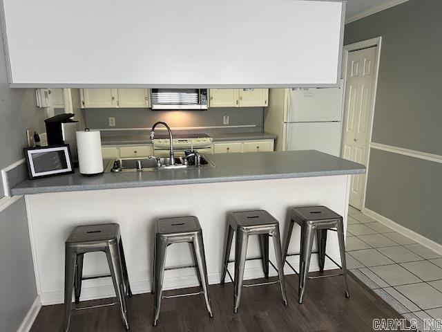 kitchen with baseboards, a kitchen bar, stainless steel microwave, a sink, and freestanding refrigerator