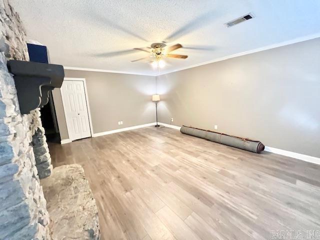 unfurnished living room with a textured ceiling, visible vents, crown molding, ceiling fan, and wood finished floors