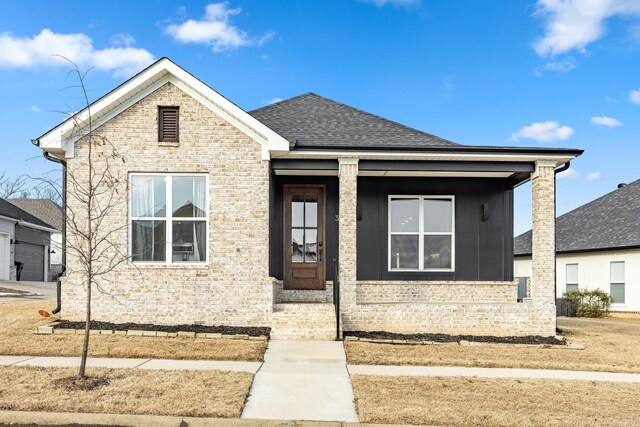 bungalow featuring brick siding and a shingled roof