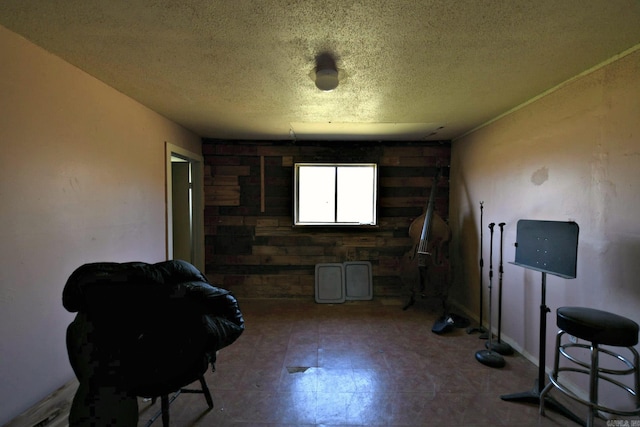 misc room featuring a textured ceiling, tile patterned floors, and wooden walls