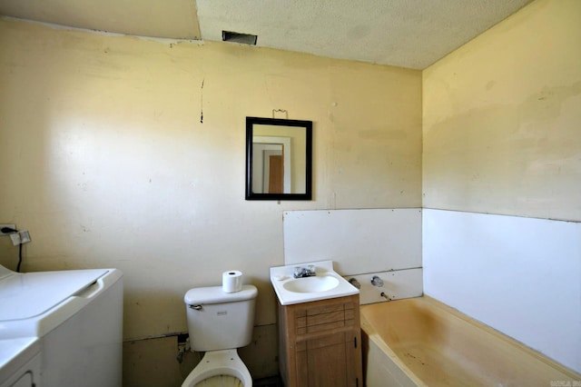 full bath with a bathing tub, toilet, vanity, and a textured ceiling