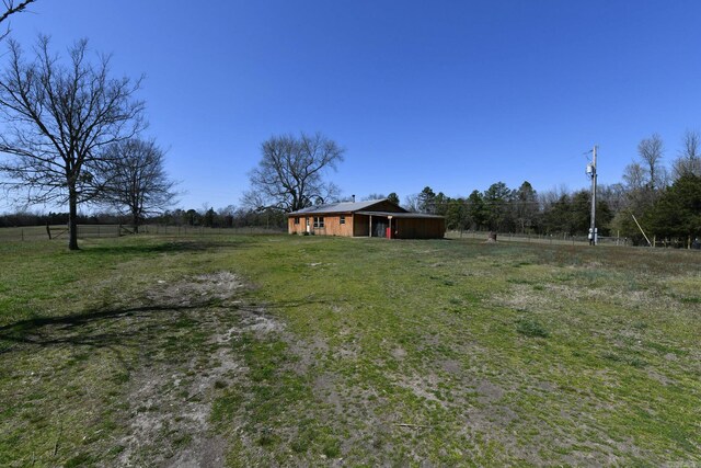 view of yard featuring a rural view, fence, and an outdoor structure