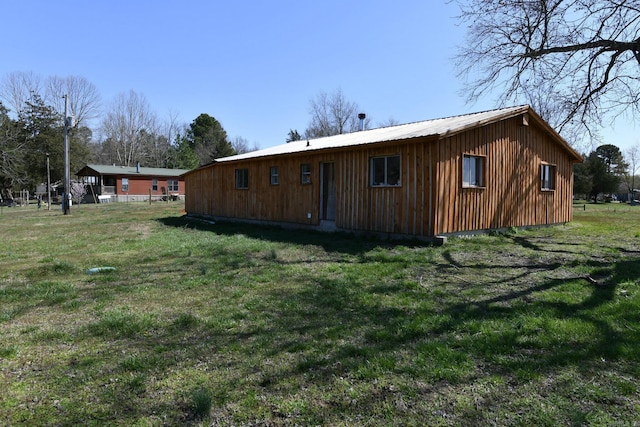 rear view of house with metal roof and a yard