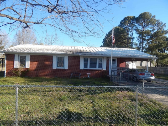 view of front facade with driveway, a front yard, brick siding, metal roof, and a carport