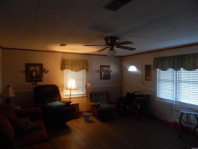 living room with crown molding, visible vents, wood finished floors, and a ceiling fan