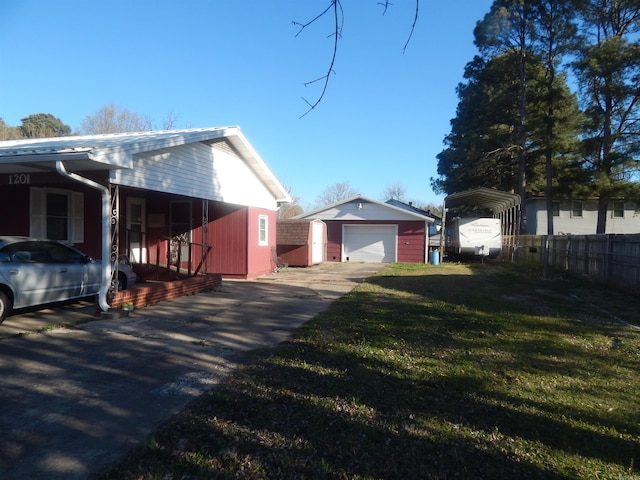view of side of home with fence, a detached garage, a lawn, driveway, and an outbuilding