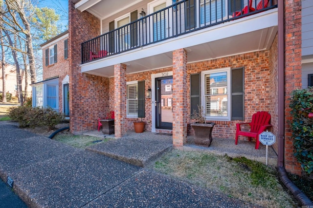 doorway to property featuring a porch and brick siding