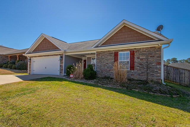 view of front of home featuring driveway, stone siding, a front yard, and an attached garage
