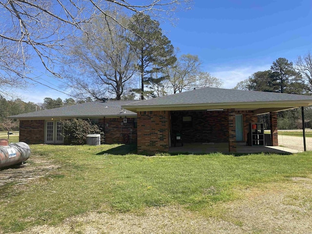 exterior space featuring a patio, french doors, central AC unit, a front lawn, and brick siding