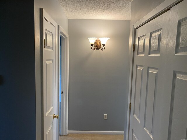 corridor with baseboards, a textured ceiling, and a notable chandelier