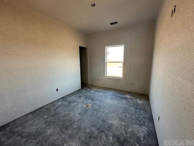 spare room with concrete floors and a textured wall