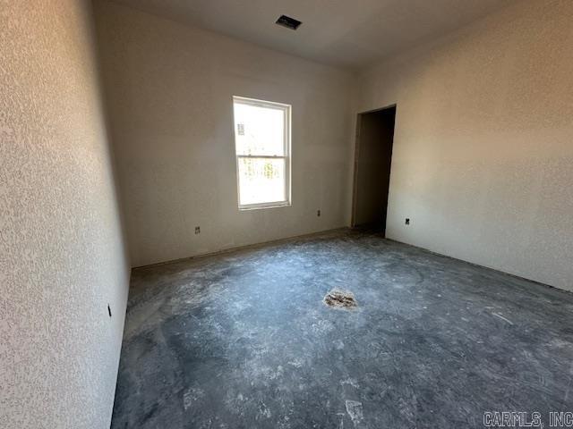 empty room featuring unfinished concrete flooring and a textured wall
