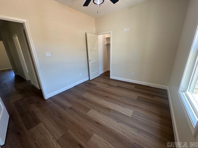 1000 Duke Dr, Bauxite, AR 72011 - unfurnished bedroom with dark wood-style floors, baseboards, a spacious closet, and ceiling fan