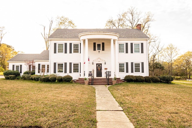 greek revival inspired property featuring a front yard and a chimney