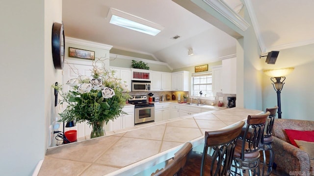 kitchen featuring crown molding, a peninsula, a kitchen breakfast bar, and stainless steel appliances