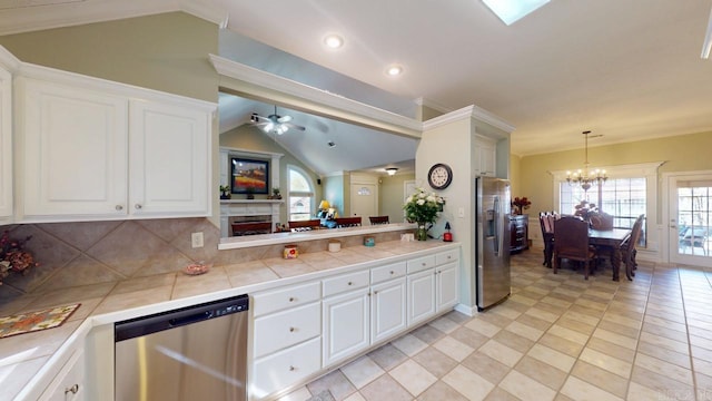 kitchen with tasteful backsplash, lofted ceiling, stainless steel appliances, ceiling fan with notable chandelier, and white cabinets