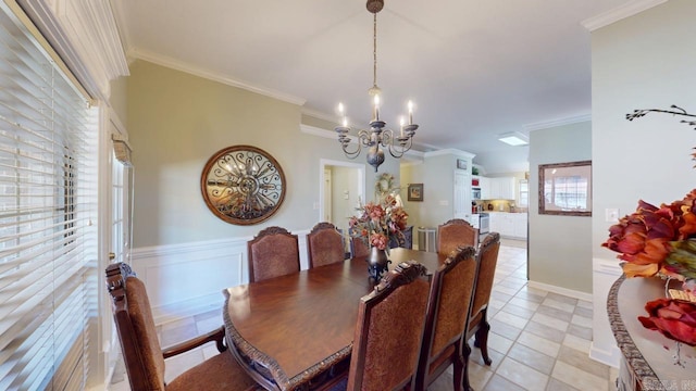 dining space with a wainscoted wall, ornamental molding, a decorative wall, and an inviting chandelier