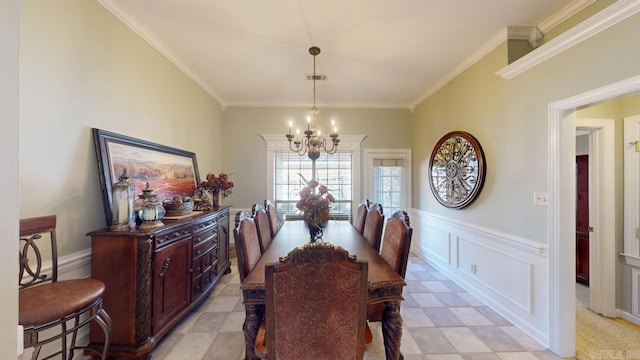 dining room with crown molding, a chandelier, wainscoting, a decorative wall, and visible vents