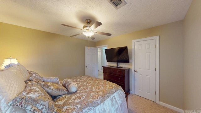 bedroom featuring baseboards, visible vents, light colored carpet, and a textured ceiling