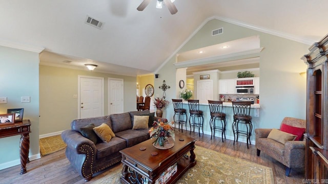 living area featuring a ceiling fan, crown molding, vaulted ceiling, and visible vents