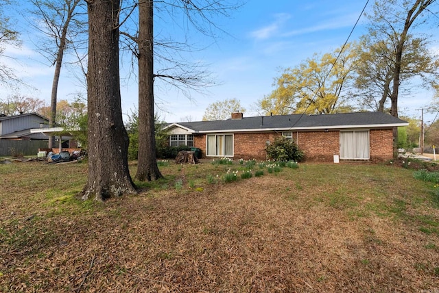 back of property with brick siding, a yard, and a chimney