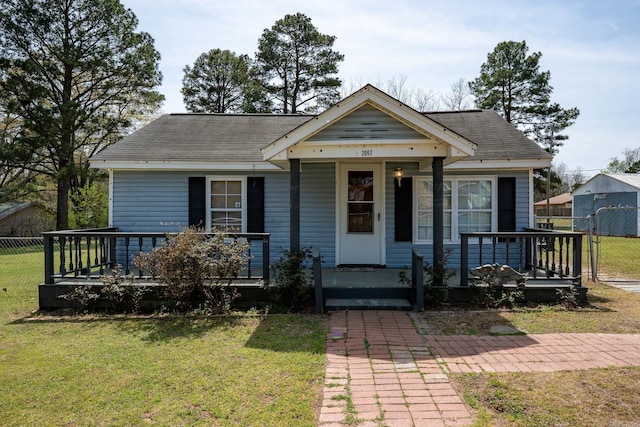 bungalow-style home featuring a front yard, roof with shingles, a porch, and fence