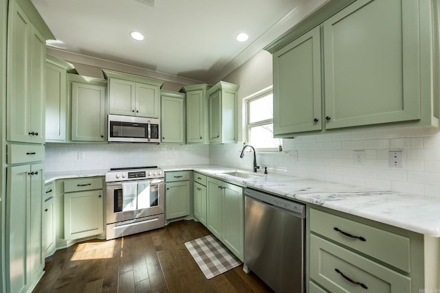 kitchen with a sink, green cabinetry, backsplash, and appliances with stainless steel finishes
