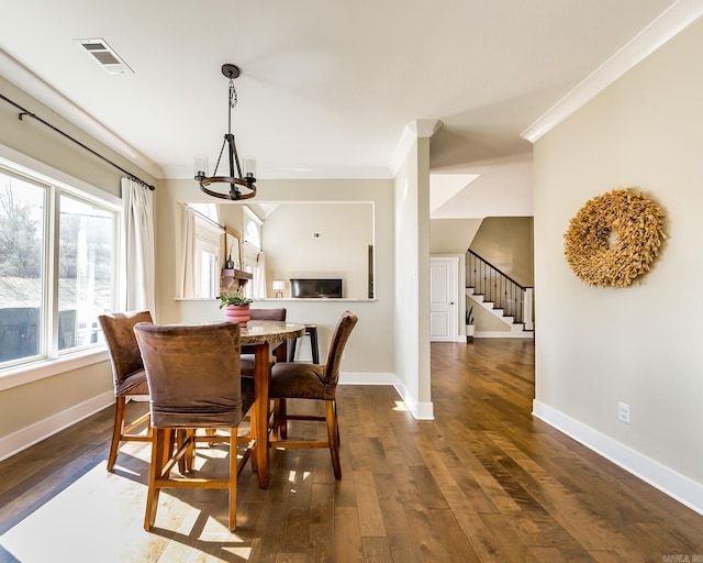 dining space featuring dark wood finished floors, visible vents, crown molding, and an inviting chandelier