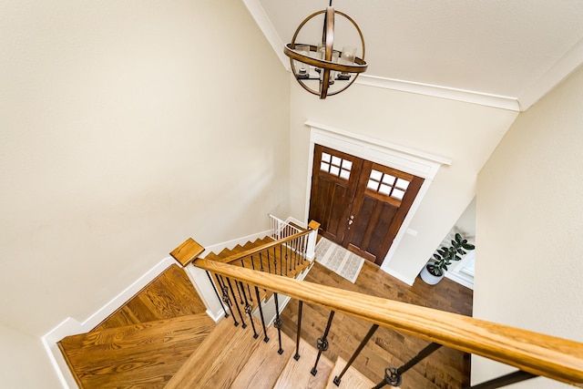 entryway with baseboards, crown molding, wood finished floors, and a notable chandelier