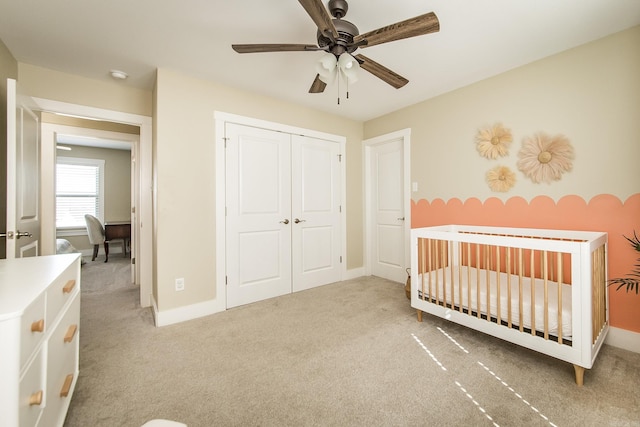 bedroom with carpet flooring, a crib, baseboards, and a closet