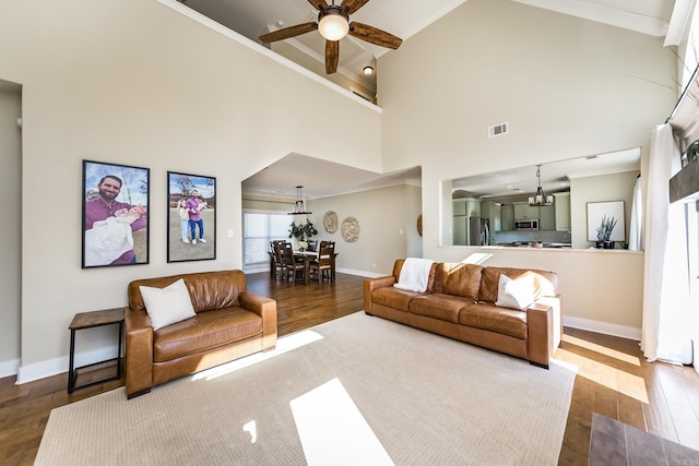living room with wood finished floors, baseboards, ceiling fan with notable chandelier, visible vents, and ornamental molding