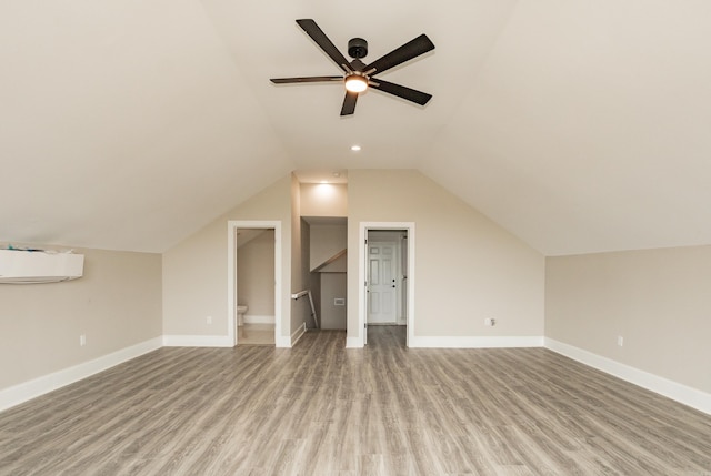 additional living space with a wall mounted AC, wood finished floors, a ceiling fan, baseboards, and lofted ceiling