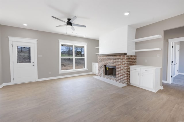 unfurnished living room with baseboards, recessed lighting, a ceiling fan, a brick fireplace, and light wood finished floors