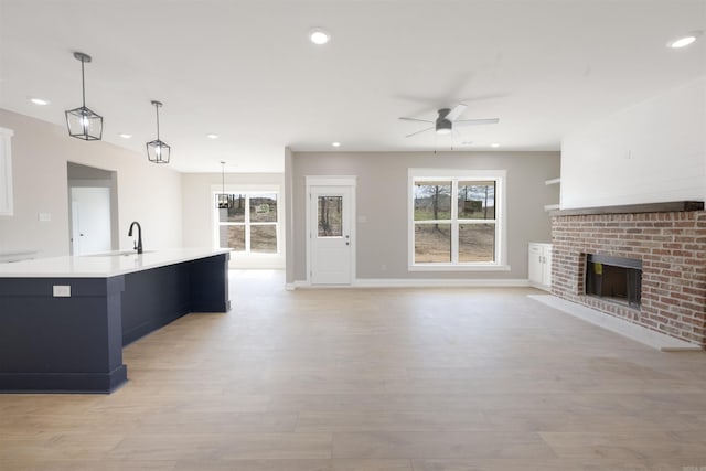 unfurnished living room featuring a healthy amount of sunlight, a ceiling fan, recessed lighting, and a fireplace