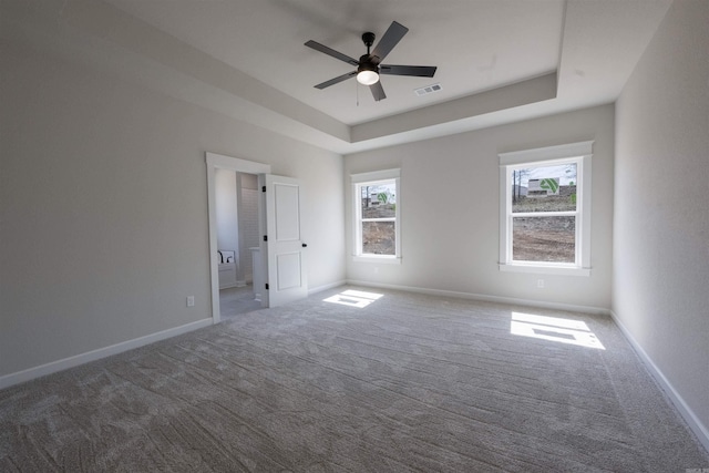 unfurnished room with visible vents, ceiling fan, a raised ceiling, and carpet