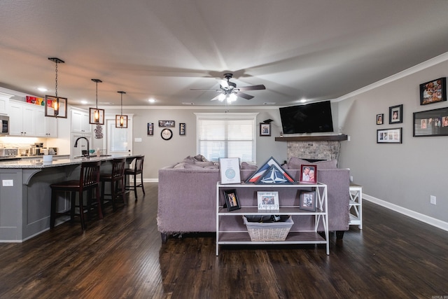 living room with a stone fireplace, dark wood-style floors, ceiling fan, and baseboards