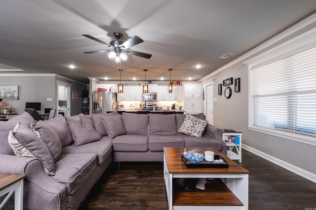 living area with ornamental molding, baseboards, dark wood-style floors, visible vents, and ceiling fan